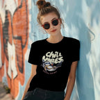 Woman wearing Chill Vibes sloth t-shirt leaning on a wall with sunglasses and messy bun